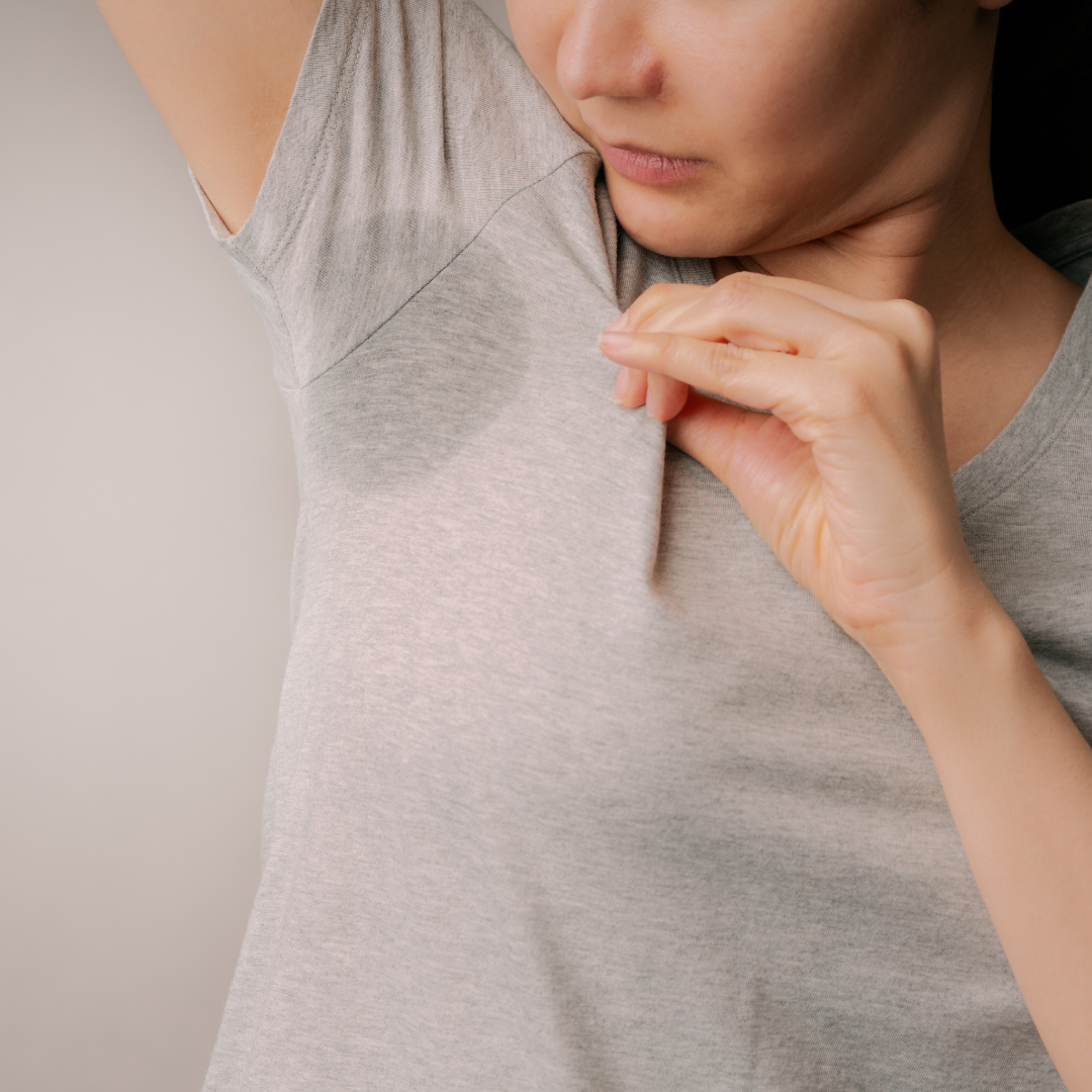 Frau mit Schweißflecken unter den Achseln