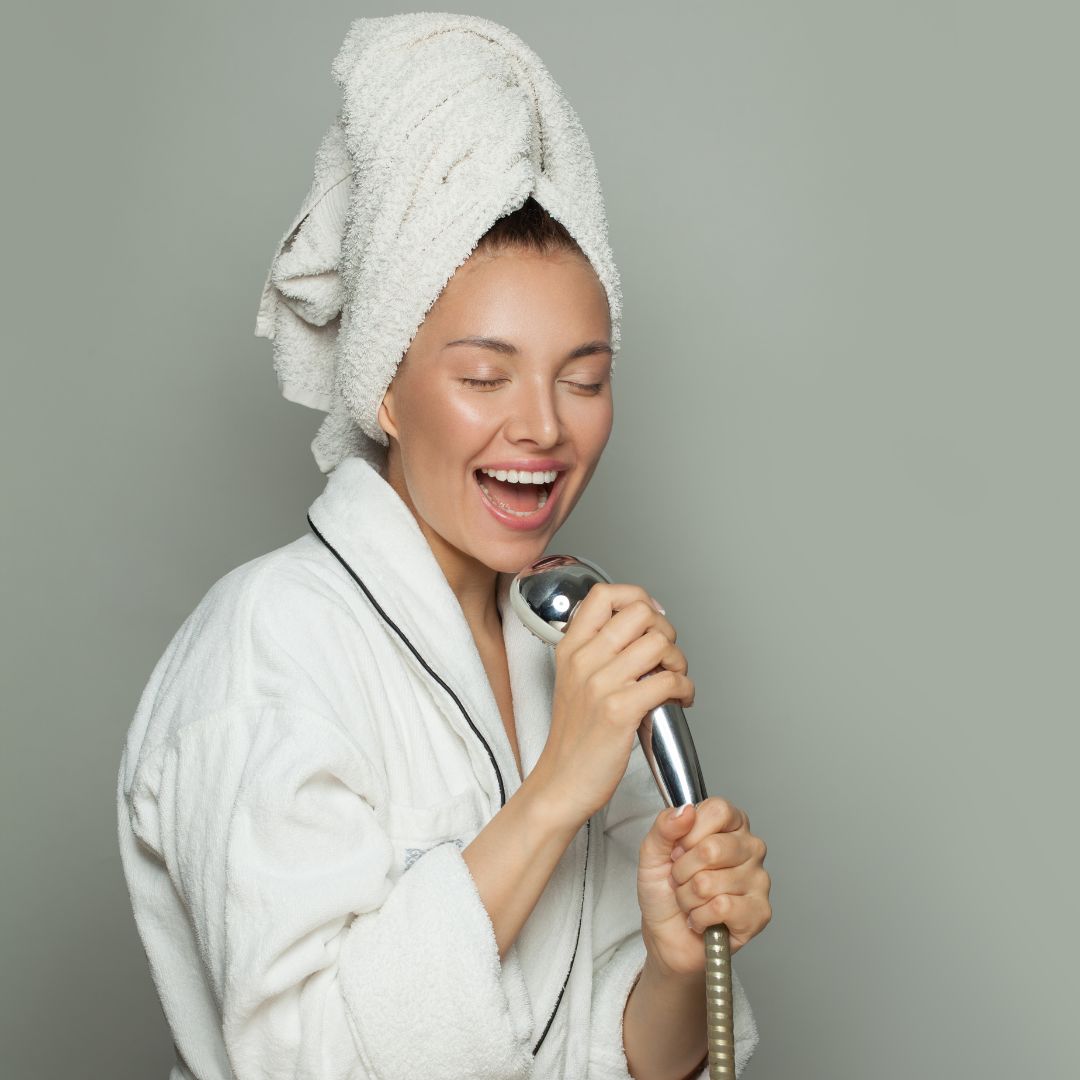 Frau singt in Duschkopf Duschroutine Körperpflege