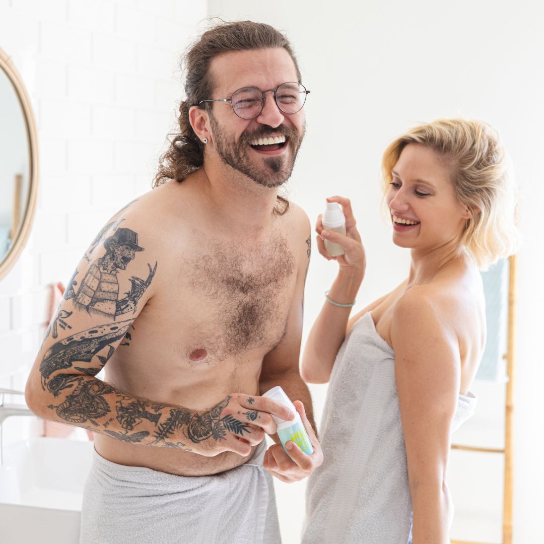 Lachendes Paar besprüht sich mit HOLY PIT Bodyspray