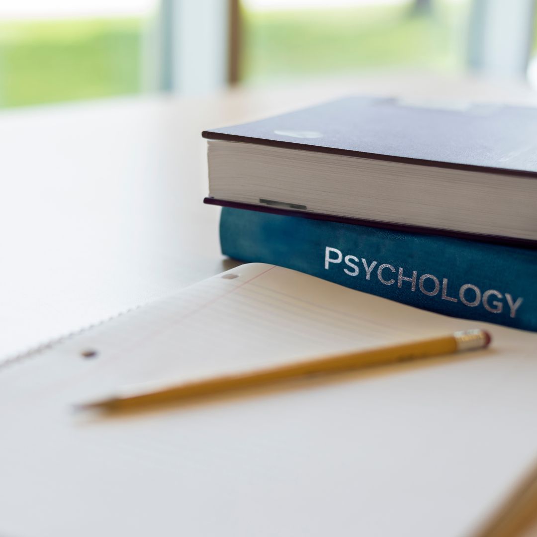 Block im Vordergrund und Bücher zu Psychologie des Schwitzens im Hintergrund