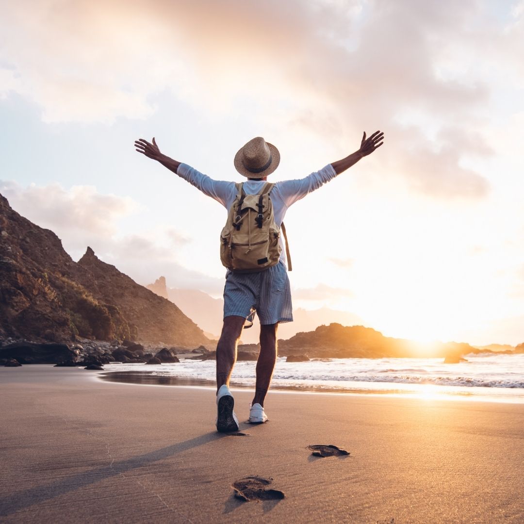 Mann am Strand breitet die Arme aus