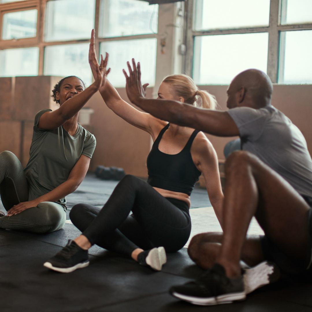 Gruppe macht High Five und lacht im Fitnessstudio