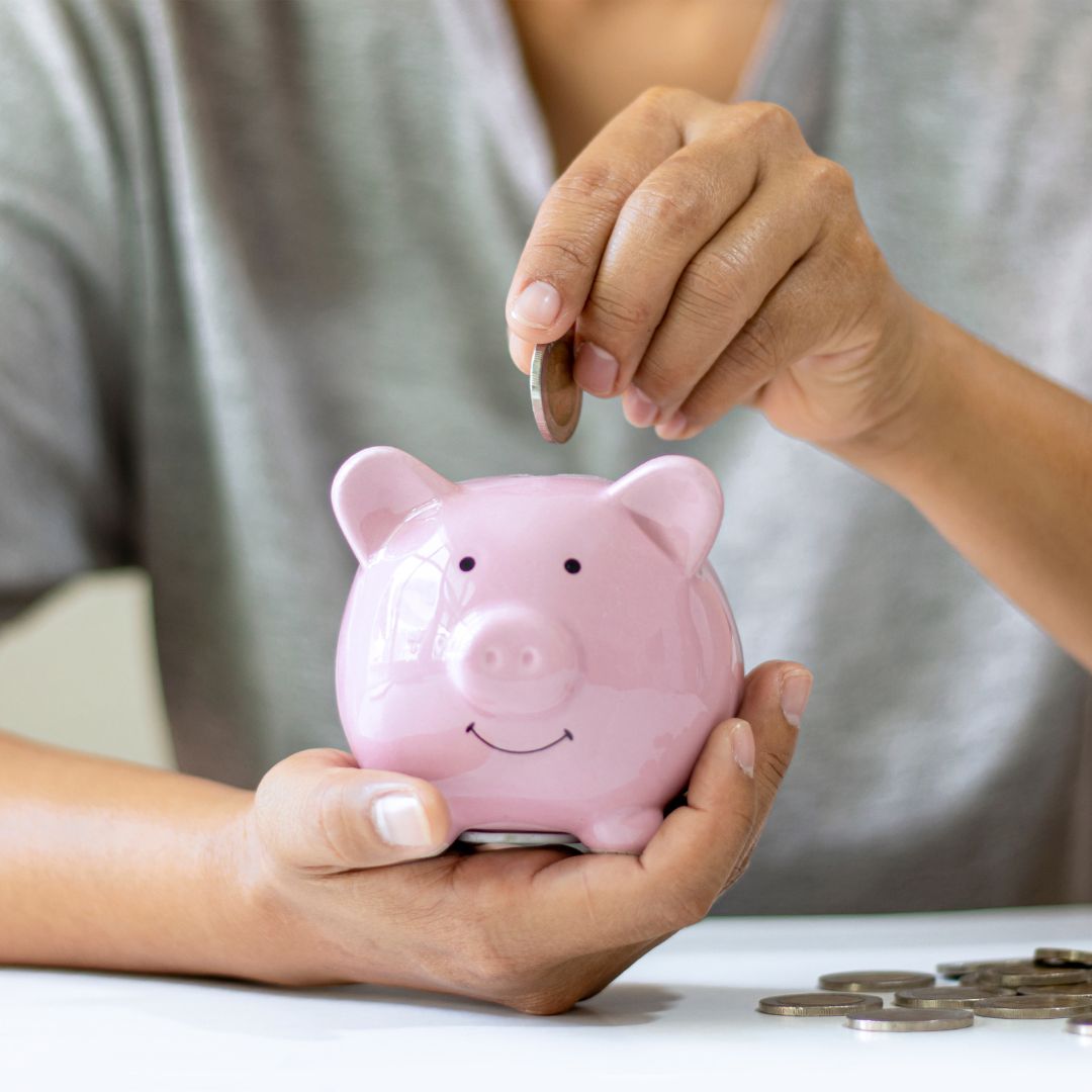 Person wirft Geld in Sparschwein zum Geld sparen