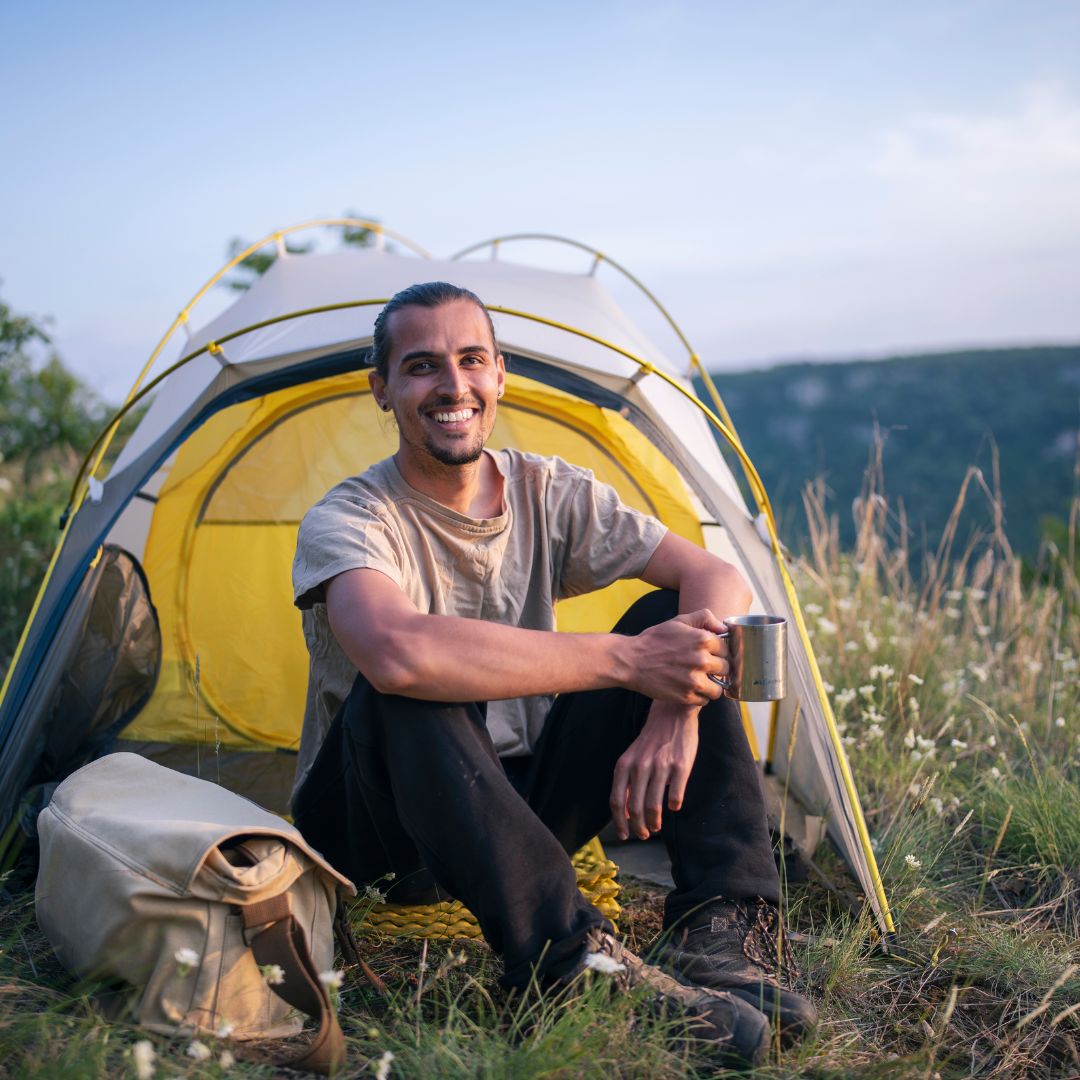 Mann beim Camping vor Zelt