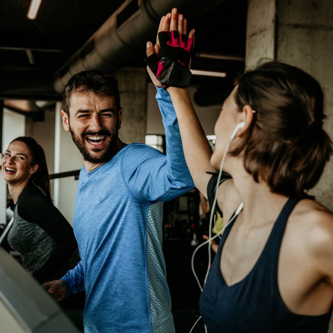 Mann und Frau schwitzen beim Sport und klatschen lachend ein