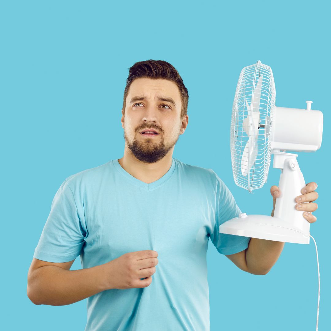 Mann mit Ventilator beim Schwitzen im Sommer