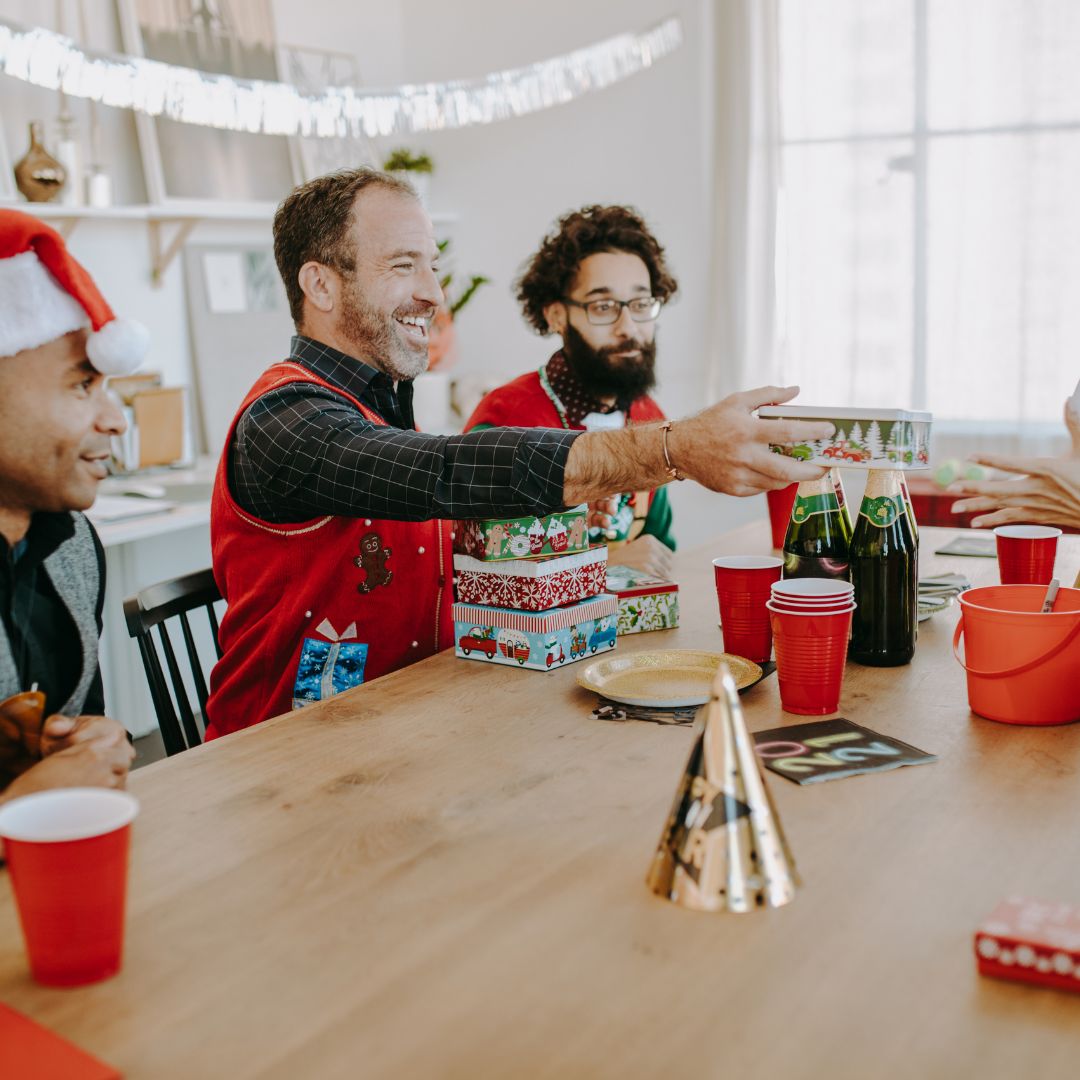 Kollegen überreichen sich Wichtelgeschenk fürs Büro